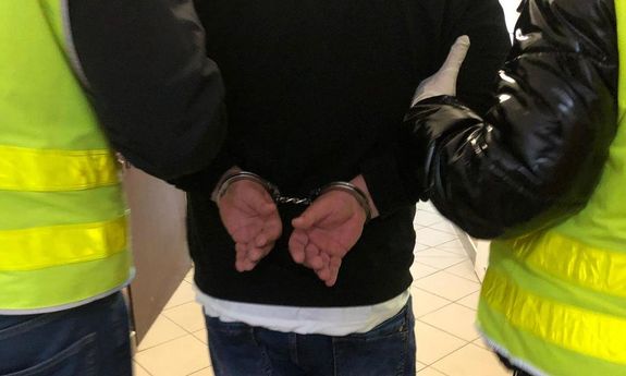 policjanci idą z zatrzymanym.
