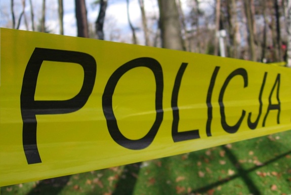 Czarny napis Policja na żółtej taśmie.
