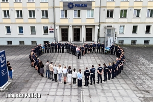 Policjanci i pracownicy cywilni stoją przed budynkiem komendy tworząc kształt serca.