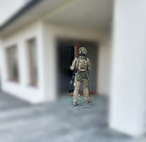 Policjant BOA przed drzwiami tarasowymi budynku.