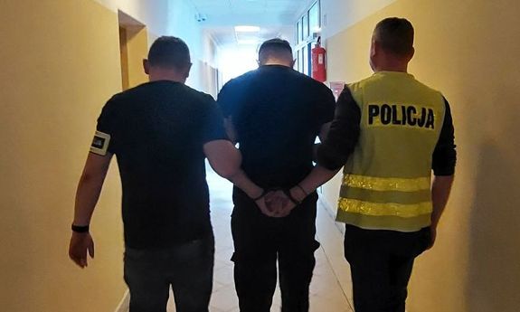dwóch policjantów idzie z zatrzymanym.