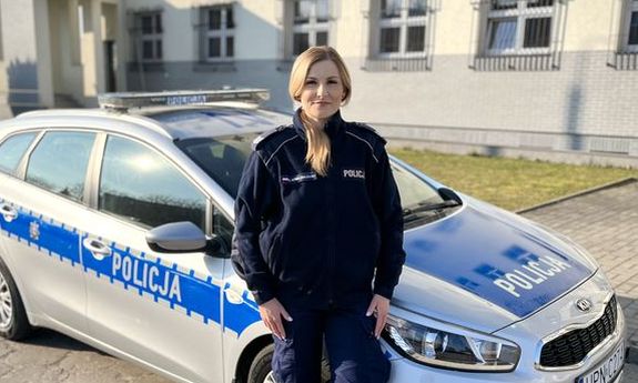 policjantka stoi przed radiowozem.