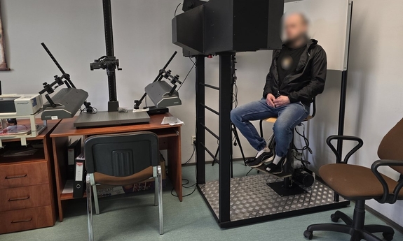 Zdjęcie przedstawia mężczyznę siedzącego na krześle u technika kryminalistyki.