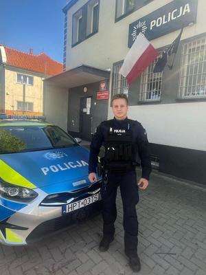 Policjant stoi przy radiowozie.