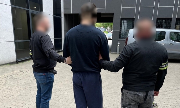 Dwaj funkcjonariusze prowadzą zatrzymanego.