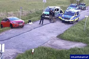 Miejsce zatrzymania mężczyzny. Samochód napastnika i radiowozy policji i straży granicznej na drodze.