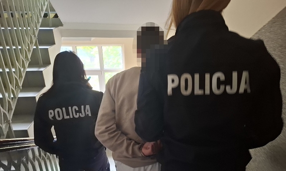 Dwie policjantki sprowadzają po schodach zatrzymanego.