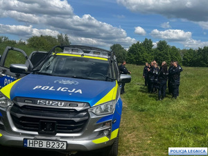 Radiowóz policyjny i policjanci podczas odprawy na zboczu góry.