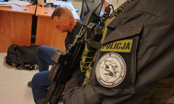 policjant stoi obok zatrzymanego.