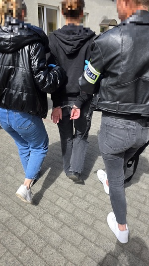 Dwie nieumundurowane policjantki prowadzą zatrzymaną. Widok z tyłu.