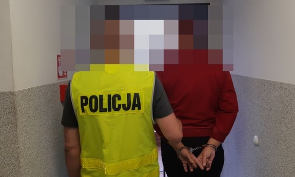 Policjant prowadzi zatrzymaną kobietę,