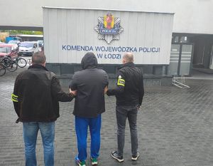 Dwaj nieumundurowani policjanci prowadzą zatrzymanego.