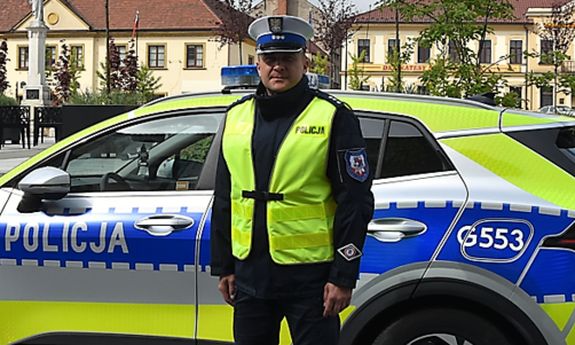 policjant stoi przed radiowozem.