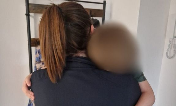 Policjantka trzyma chłopca na rękach i go tuli.