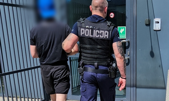 Funkcjonariusz prowadzi zatrzymanego.