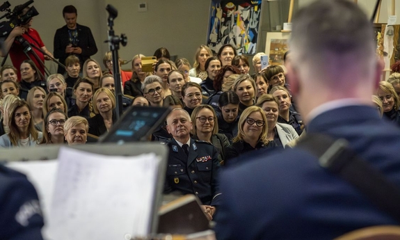 Goście koncertu siedzą na krzesłach na sali.