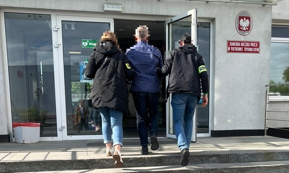Dwaj funkcjonariusze prowadzą zatrzymanego.