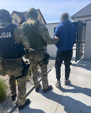 policjanci idą z zatrzymanym.