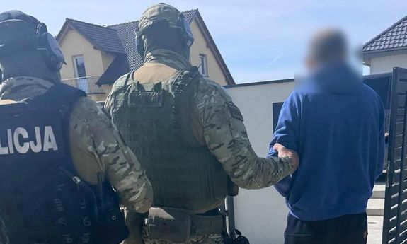 policjanci prowadzą zatrzymanego.