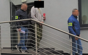 Policjanci prowadzą zatrzymanego mężczyznę.