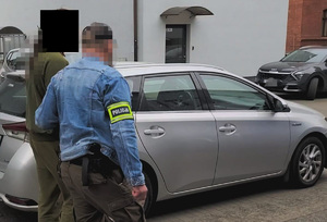 Policjanci prowadzą zatrzymanego mężczyznę.
