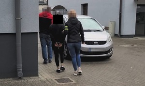 Policjanci prowadzą zatrzymanego mężczyznę.
