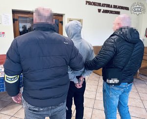 Dwaj funkcjonariusze prowadzą zatrzymanego.