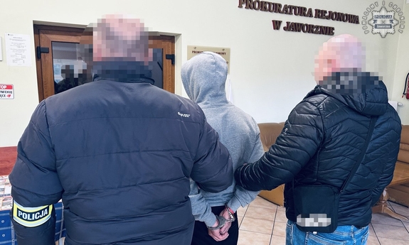 Dwaj funkcjonariusze prowadzą zatrzymanego.