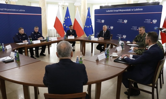 Uczestnicy odprawy służb siedzą przy stole obrad.