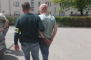 Policjant prowadzi zatrzymanego.