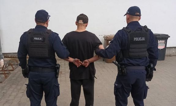 Dwaj policjanci prowadzą zatrzymanego. Widok z tyłu.
