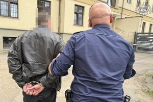 Funkcjonariusz prowadzi zatrzymanego mężczyznę.