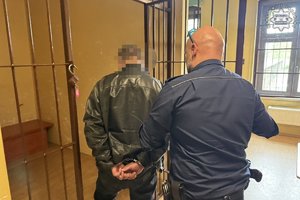 Funkcjonariusz prowadzi zatrzymanego mężczyznę.