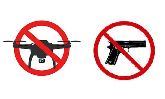 Znaki oznaczające zakaz noszenia broni i zakaz latania dronów.