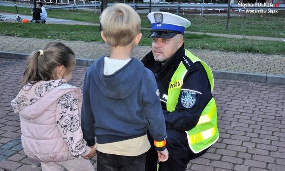 Policjant kuca przy dwójce małych dzieci.