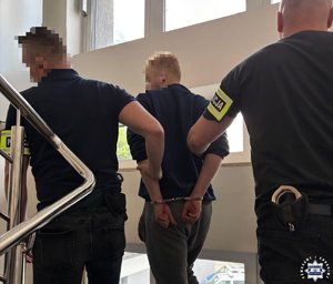 dwóch policjantów idzie z zatrzymanym.
