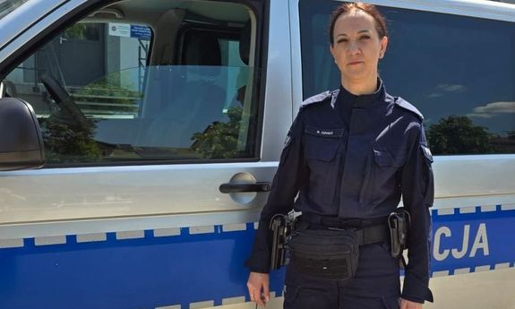 Umundurowana policjantka stoi przy radiowozie.