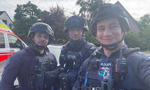 Trzech policjantów pozuje do zdjęcia.