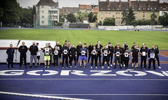 Uczestnicy biegu charytatywnego pozują do zdjęcia na bieżni stadionu.