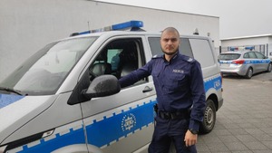 Umundurowany policjant przy radiowozie.
