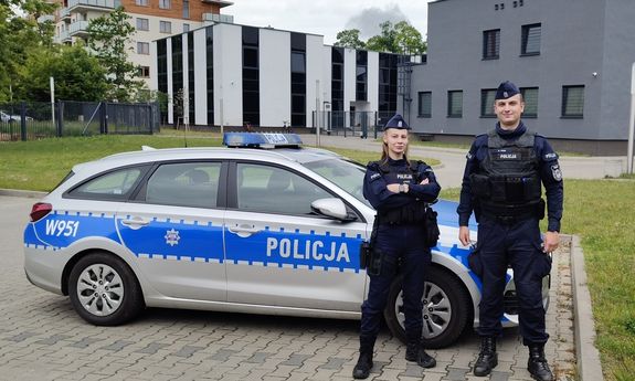 Umundurowany policjant przy radiowozie.