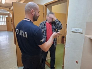 Policjant z zatrzymanym przy drzwiach aresztu.