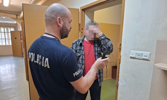 Policjant z zatrzymanym przy drzwiach aresztu.