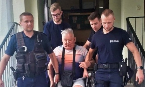 Policjanci pomagają mężczyźnie na wózku inwalidzkim.