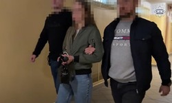 Dwaj policjanci prowadzą zatrzymana kobietę.