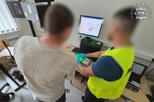 Na zdjęciu widoczny technik kryminalistyki, który skanuje linie papilarne zatrzymanego mężczyzny.