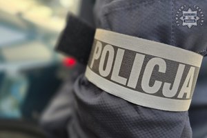 Na zdjęciu widoczna opaska z napisem POLICJA na ramieniu policjanta.