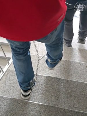 Na zdjęciu widoczny mężczyzna, który schodzi po schodach. Na nogach ma kajdanki zespolone.