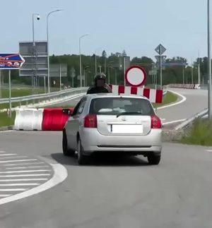 Mężczyzna siedzi na masce samochodu.