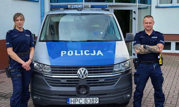 Dwoje umundurowanych policjantów stoi przy policyjnym furgonie.